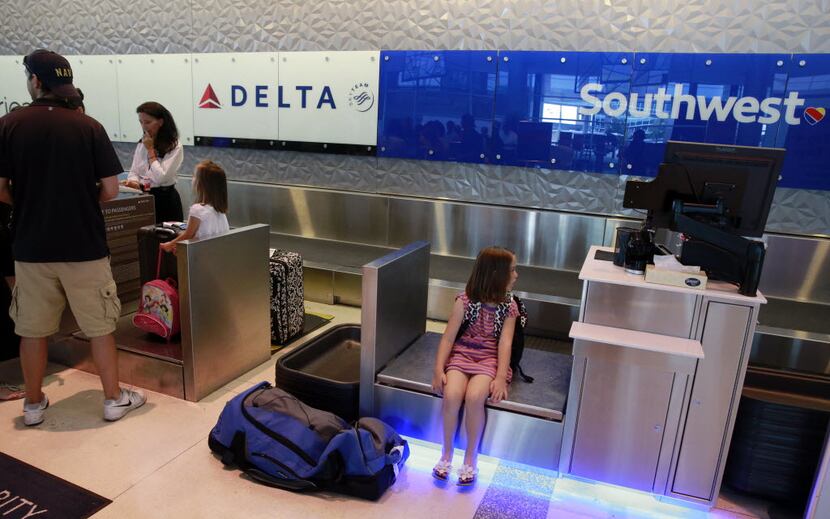 A young passenger waits on a Southwest Airlines scale as her family checks in at the...