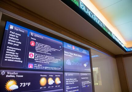 Screens show news and stock updates inside The Kitt Investing and Trading Center at the Cox...