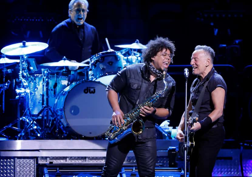 Clad in a black pearl snap shirt and black pants, Bruce Springsteen (right) performs with...