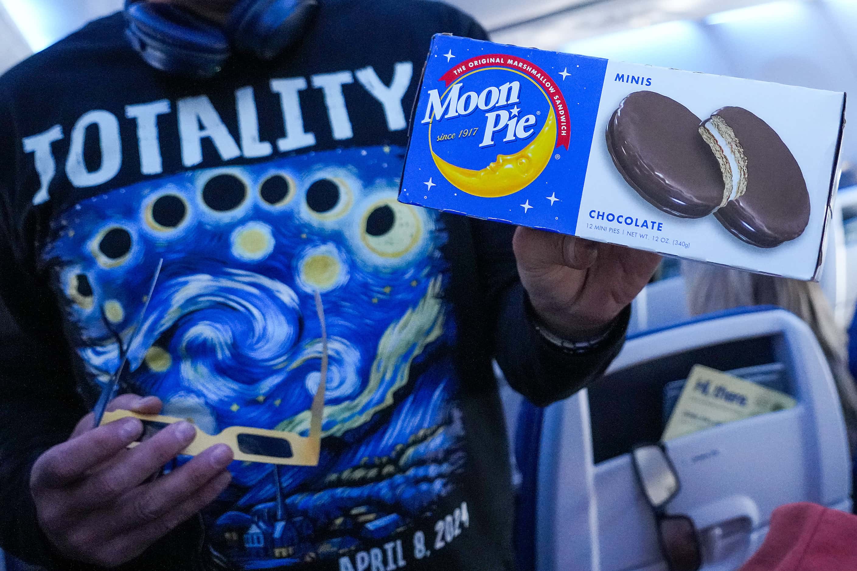 A passenger hands out Moon Pies during the early stages of a total solar eclipse on...