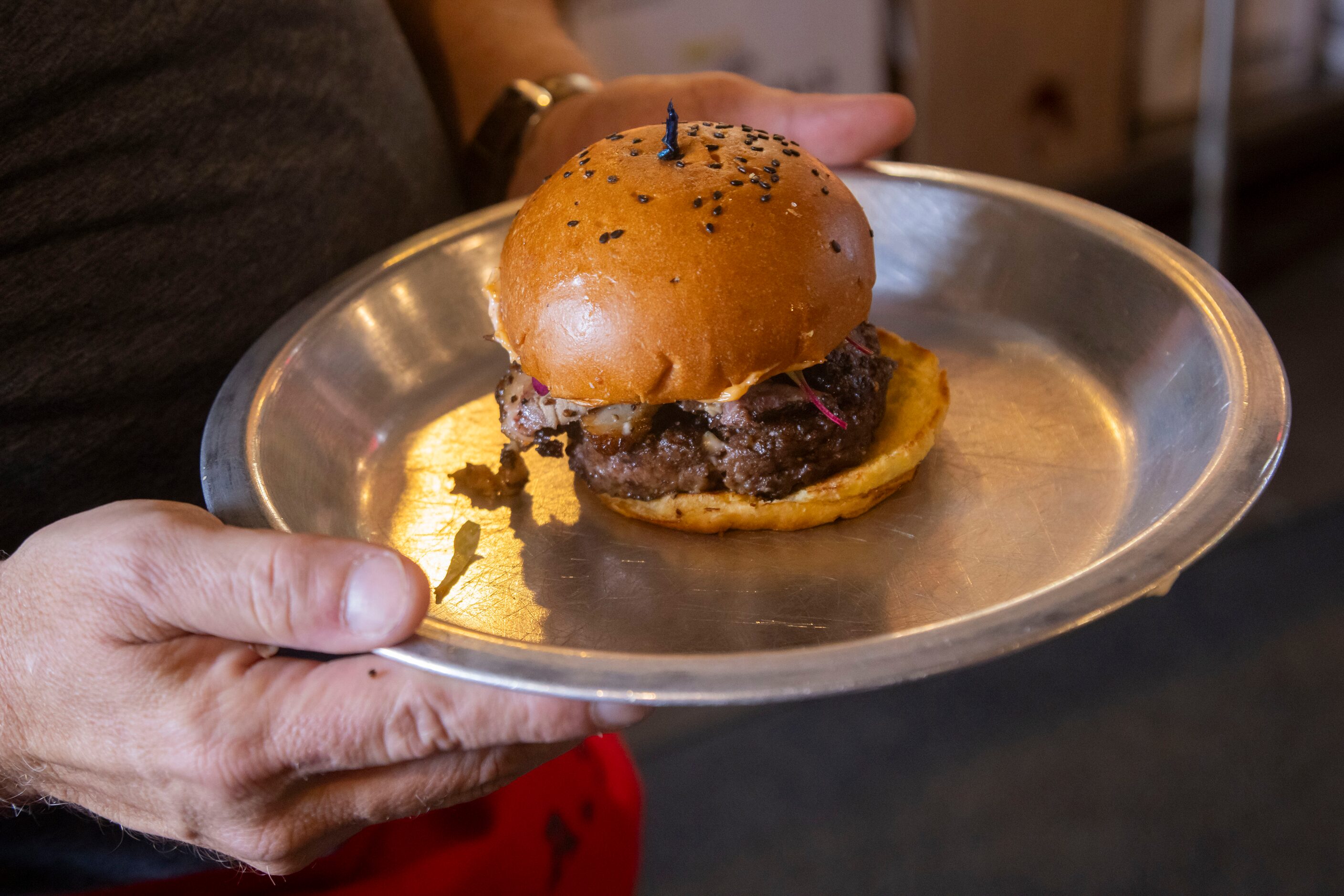 The Dallas Morning News’ Rangers reporter Evan Grant carries the Evan Grant Burger as he...