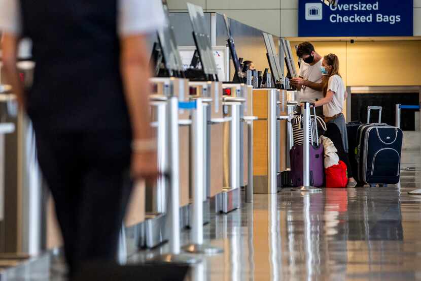 Passengers check their luggage in Terminal D at DFW International Airport in Irving, Texas,...