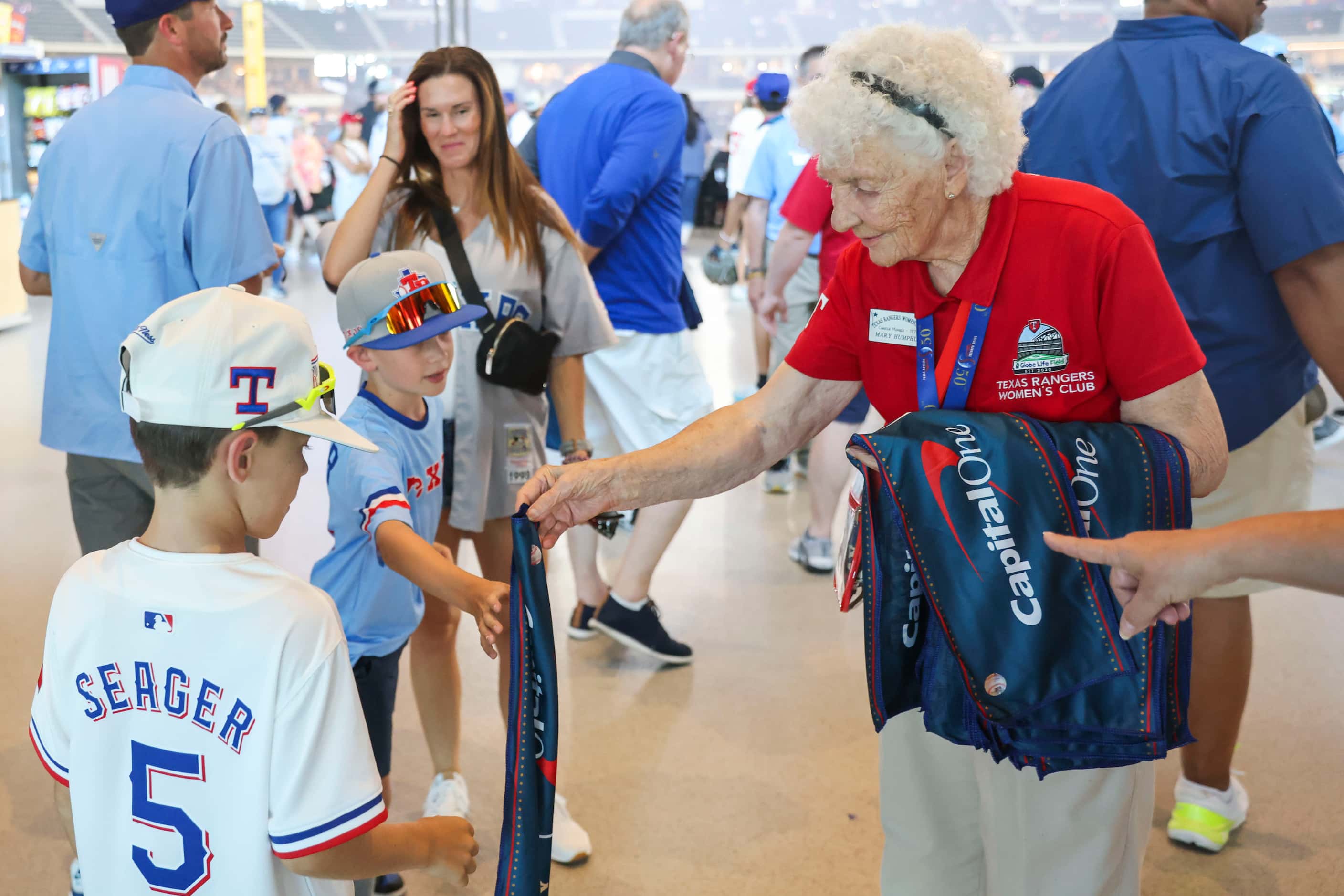 Texas Rangers Women’s Club member since 1974 Mary Humphus  hands out towels to the fans...