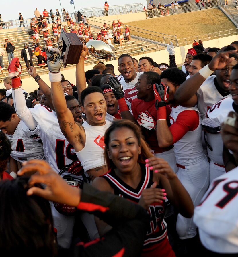 Cedar Hill players and cheerleaders celebrate with the Region 1 trophy after their 49-34 win...