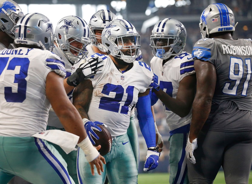 Dallas Cowboys running back Ezekiel Elliott (21) is congratulated by teammates after diving...