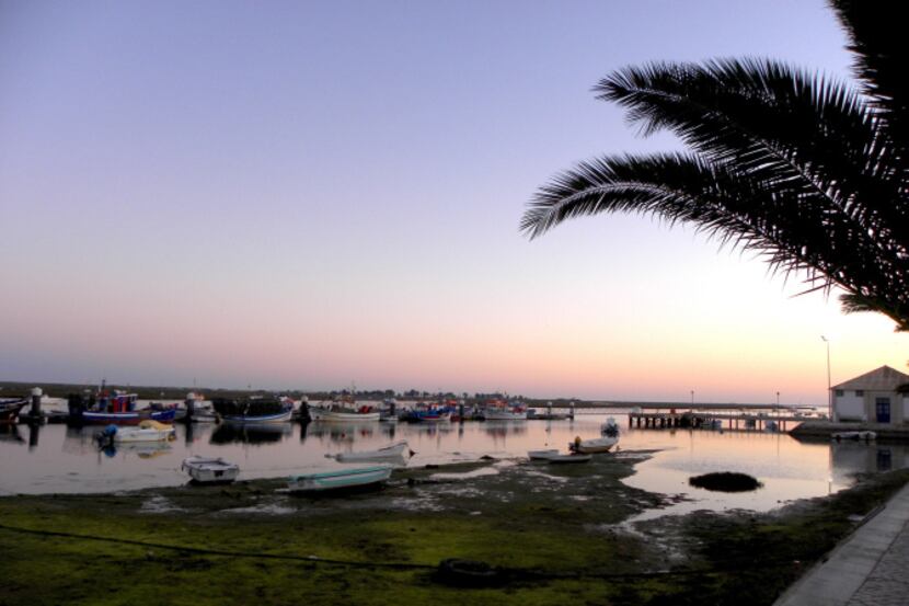The setting sun glints off the still water of the Ria Formosa lagoon during an April sunset...