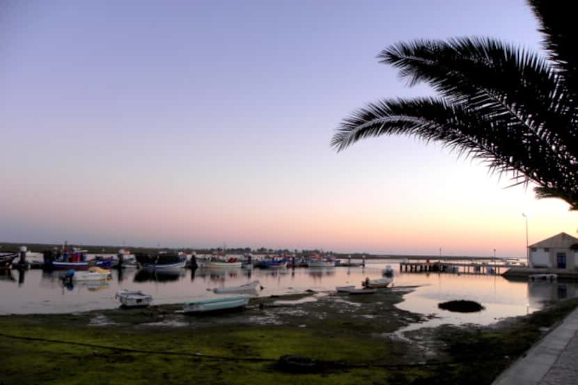 The setting sun glints off the still water of the Ria Formosa lagoon during an April sunset...