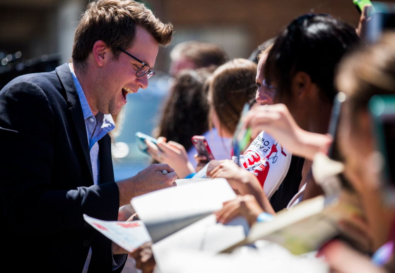 Author John Green signs autographs on the red carpet outside a promotional event for Paper...