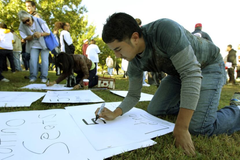 Rodolfo Guel works on a protest sign at Oak Cliff Founders Park before the start of the We...