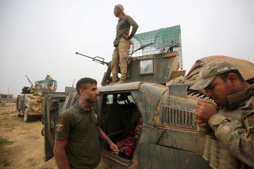 Iraqi forces wait next to their vehicles in the village of Umm Mahahir, south of Mosul, on...