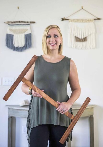 Rebekah Wright poses for a photo with her loom in front of two woven wall hangings that she...
