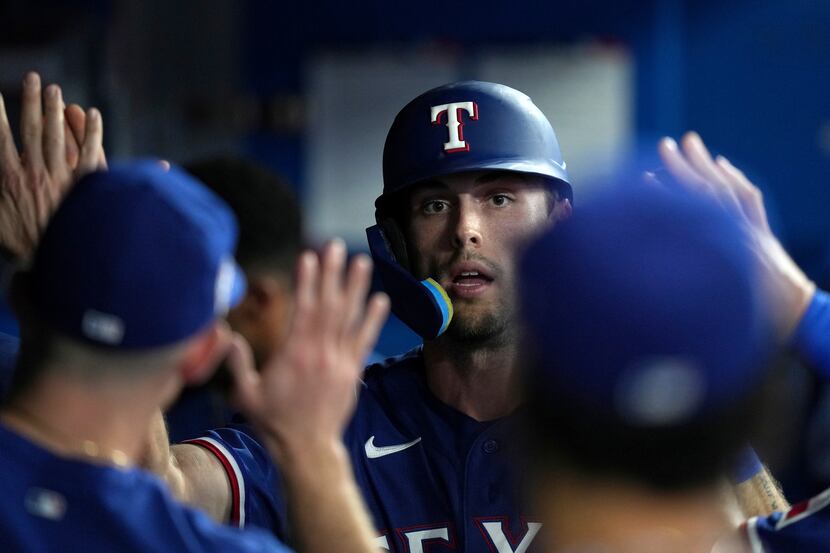 Texas Rangers left fielder Evan Carter celebrates with teammates in the dugout after scoring...