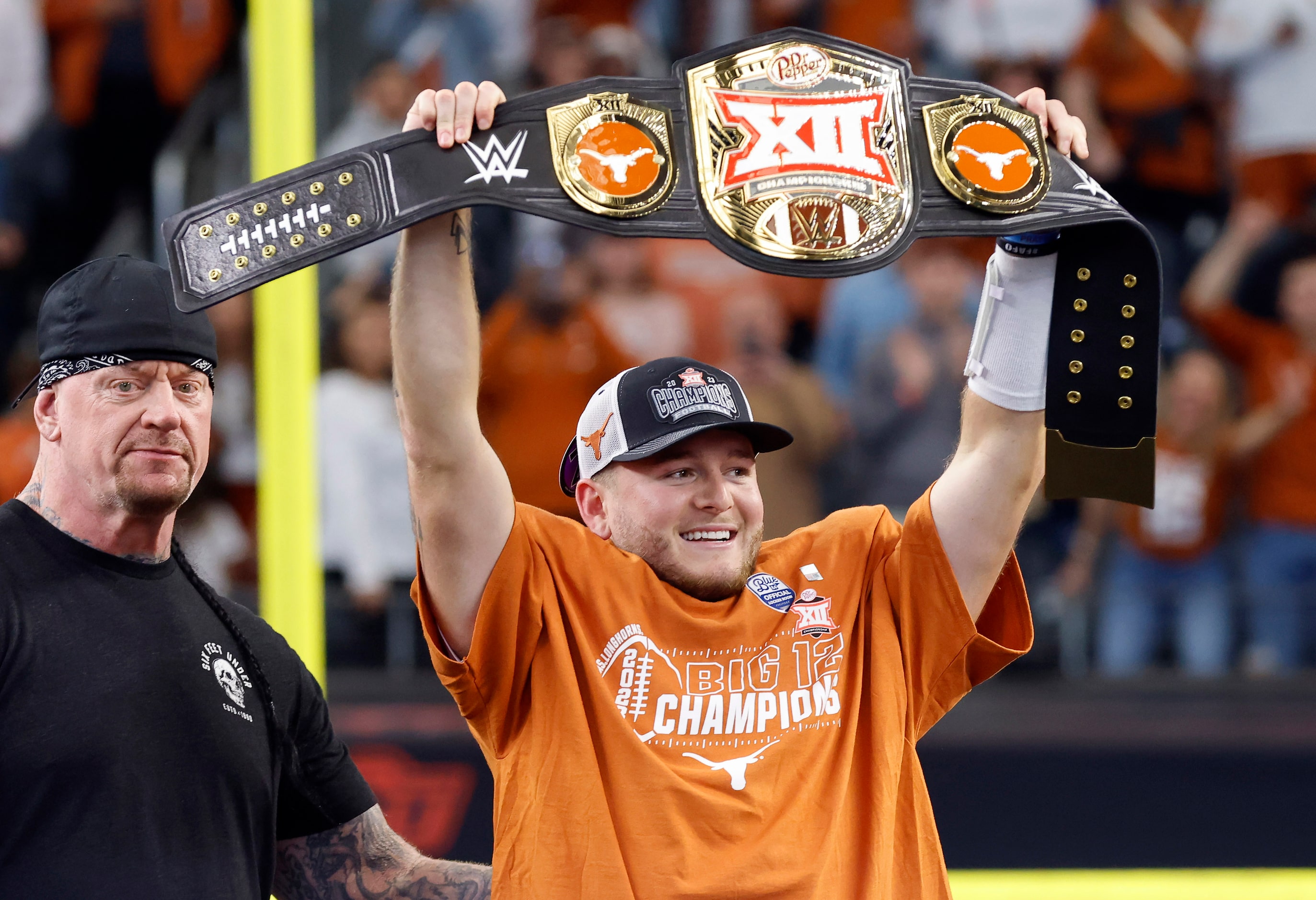 Texas Longhorns quarterback Quinn Ewers (right) hoists the WWE wrestling belt given him by...