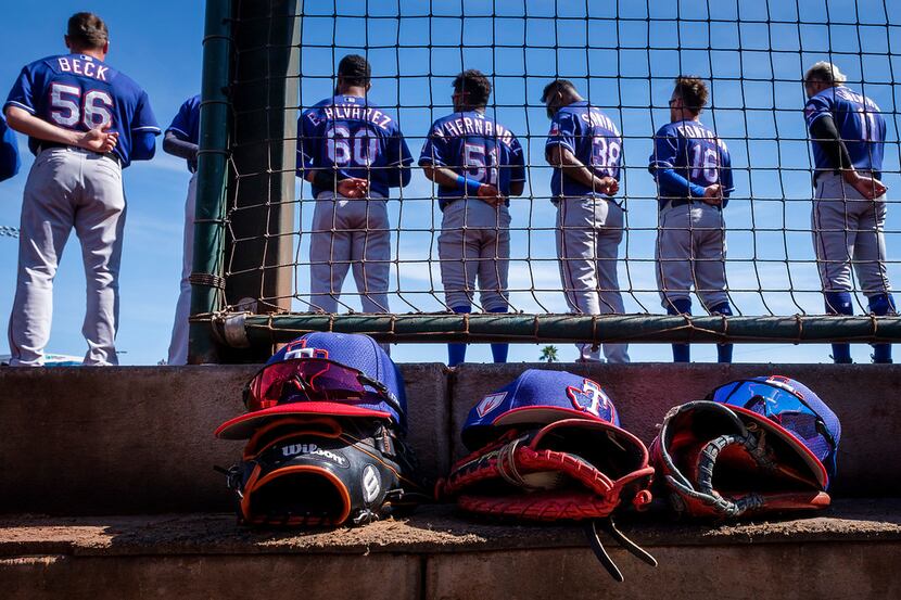 Texas Rangers players stand for the national anthem before a spring training baseball game...