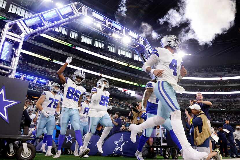 Dallas Cowboys quarterback Dak Prescott (4) and his teammates run onto the field to face the...