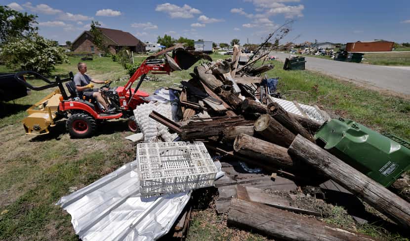 Sammie Morrell clears tornado debris from his property and stacks it outside his...