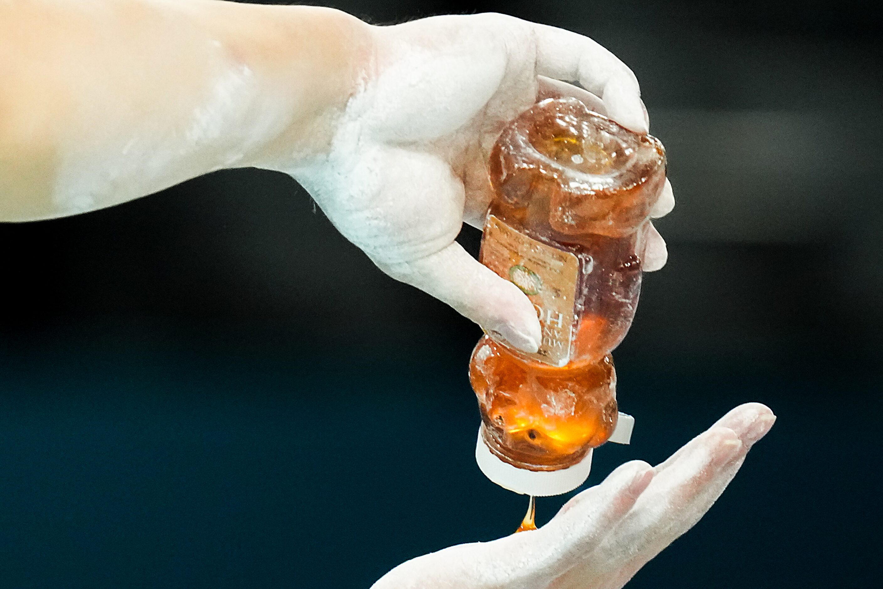 Asher Hong of the United States pours honey onto his hands before working on the parallel...