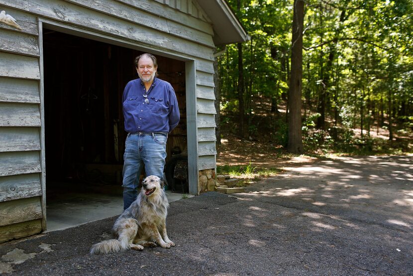 Rick Bragg, 58, stands near his mother's garage with the family dog  in Jacksonville, Ala. 