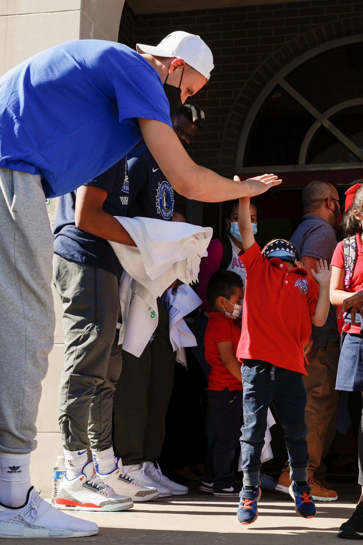 Dallas Mavericks center Kristaps Porzingis high-fives a student after the end of classes at...