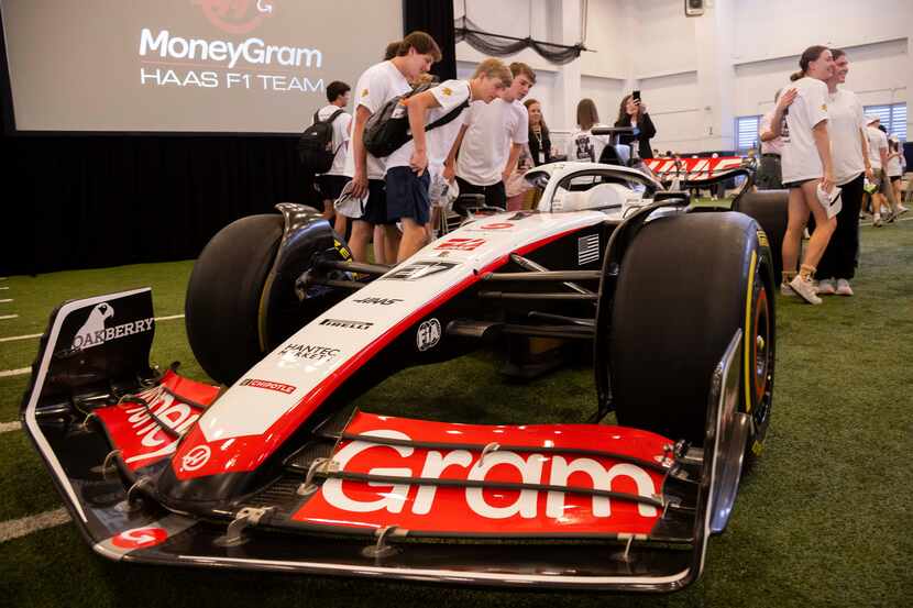 Students stop to look at and pose with a Moneygram Haas F1 Team car on display as the team...