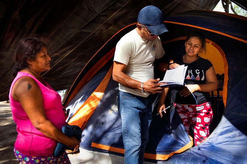 Edwin Vaquiz (center) and his wife, Alejandra (right), asylum-seekers from Honduras, tend to...