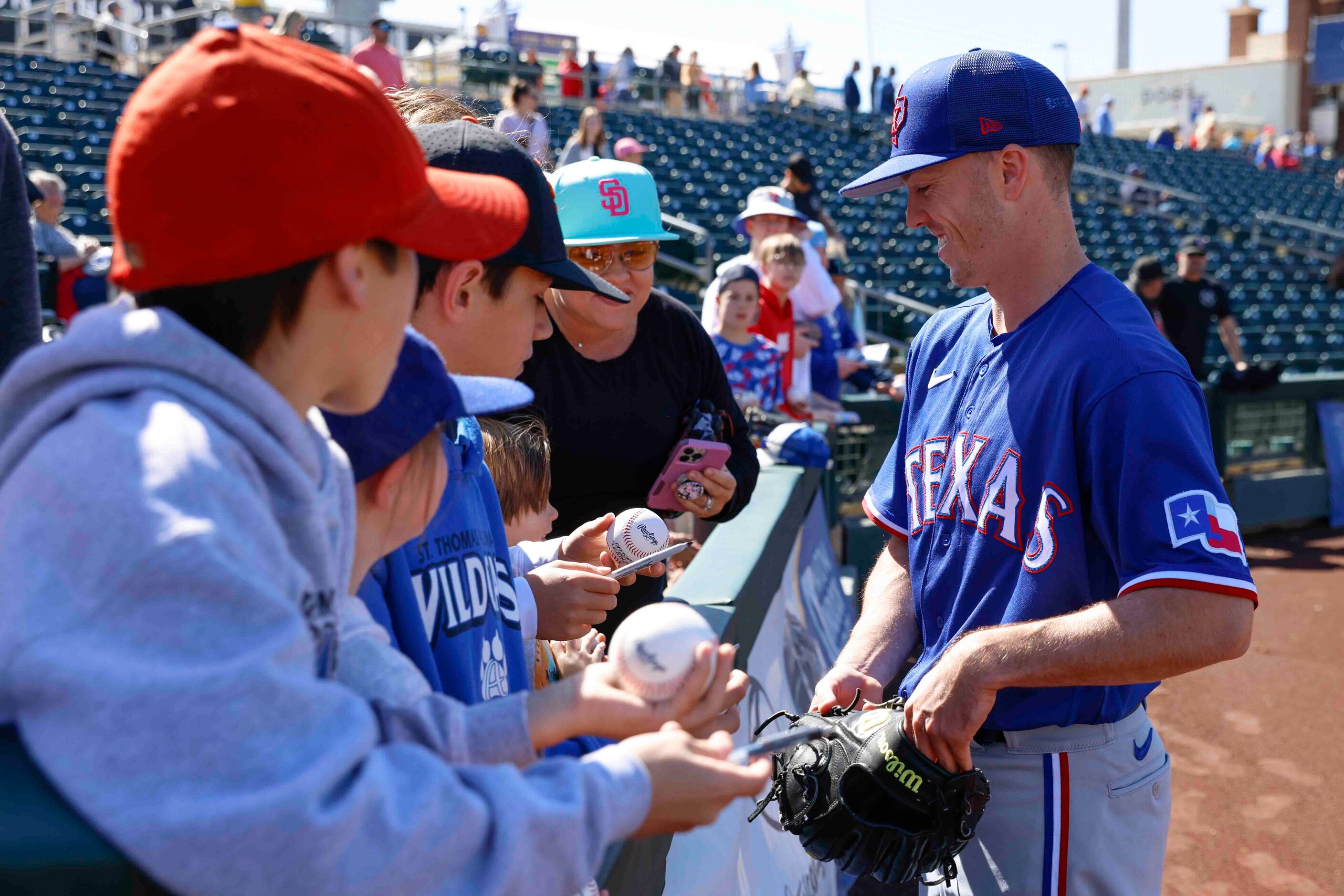 Texas Rangers pitcher Chase Lee gets set to sign autographs before a spring training game...