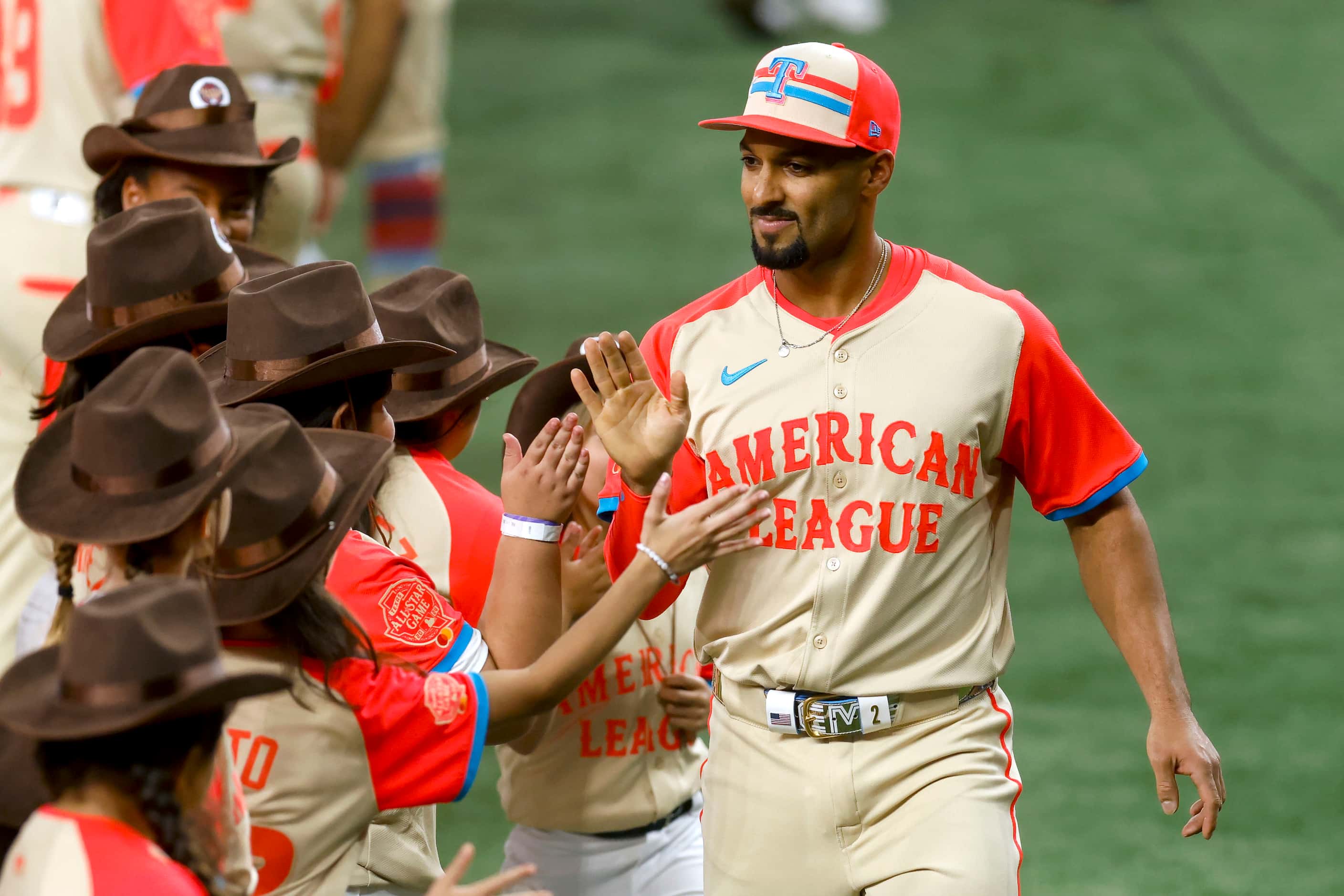 American League's Marcus Semien, of the Texas Rangers, high-fives children on the field as...