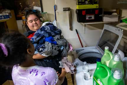 Celeste Sanchez, 18, passes a load of laundry to her cousin, Aaliyah, 10, at their home in...