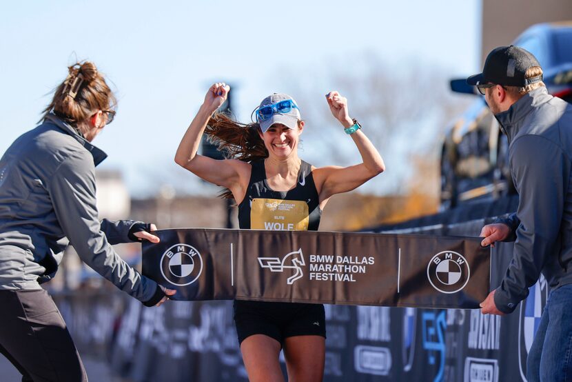 Women’s marathon finisher Jill Wolf, of Dallas, celebrates after reaching the finish line...