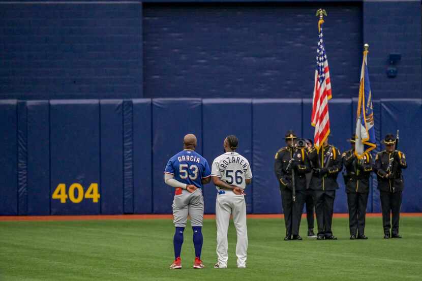Texas Rangers' Adolis Garcia (53) and Tampa Bay Rays' Randy Arozarena (56) stand for the...