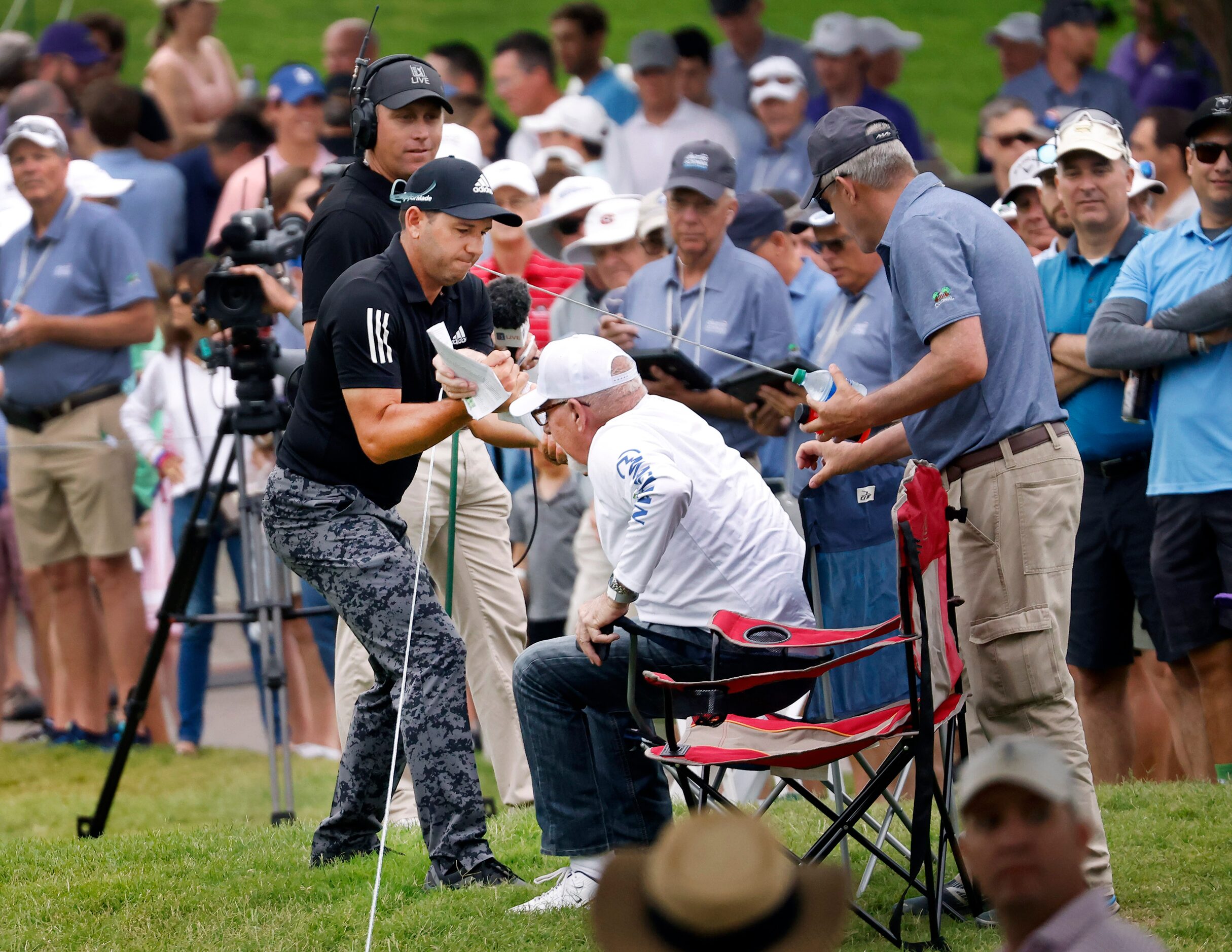 Professional golfer Sergio Garcia helps Neville Runnels of Rockwall out of his green side...