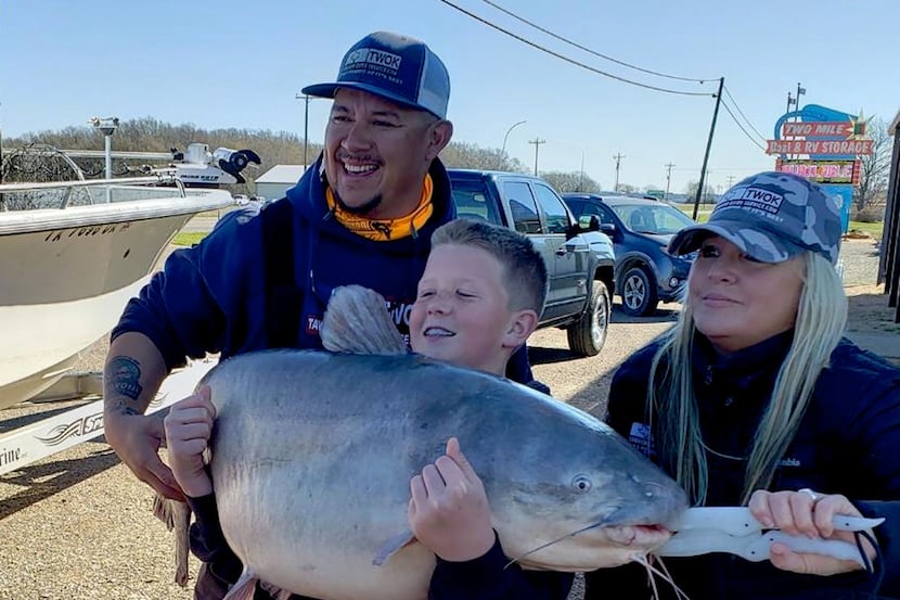 Brayden Rogers (center) displays his pending 67-pound youth state record blue catfish....