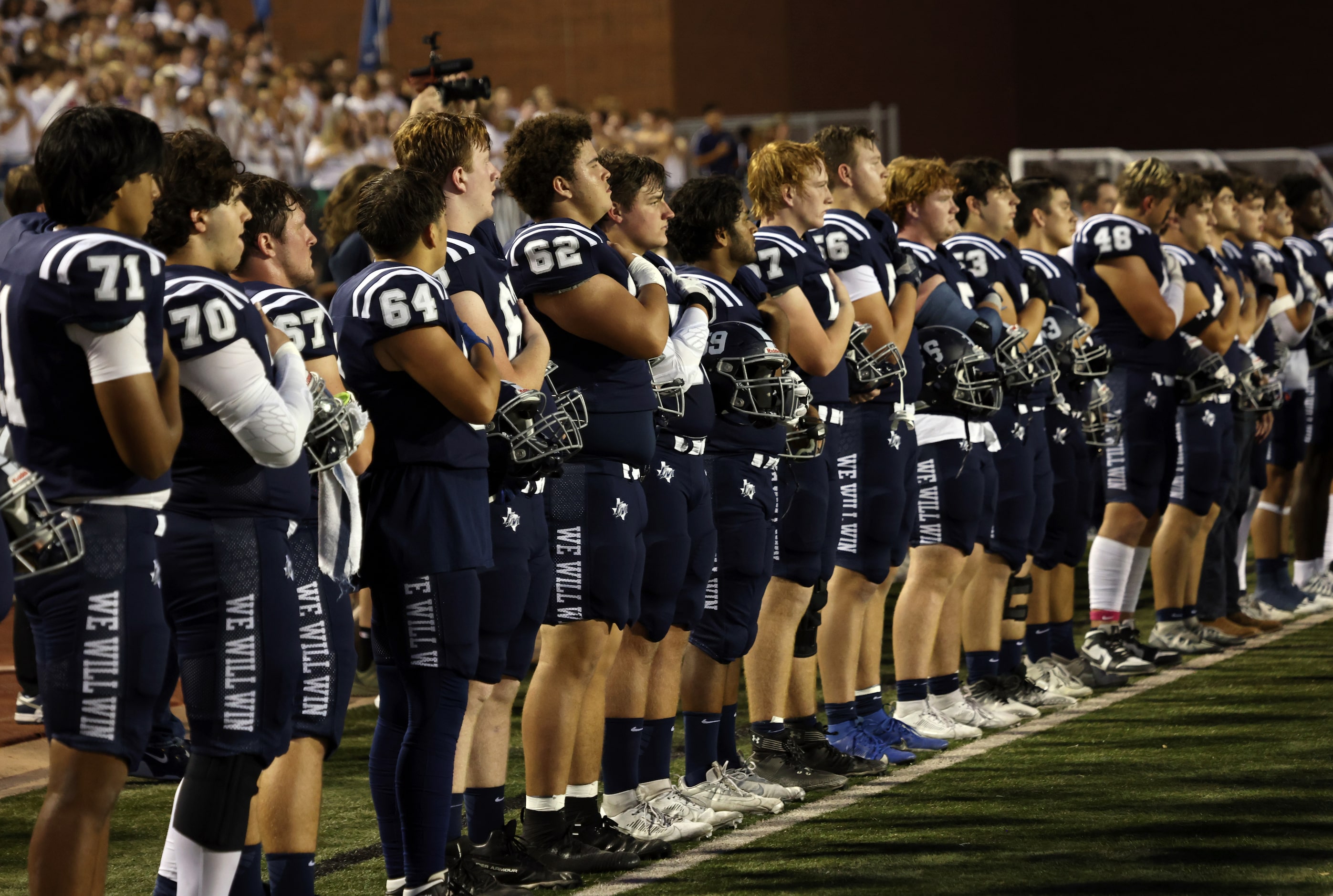 Flower Mound players pause for the playing of the national anthem before the start of their...