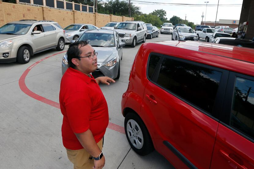 Marvin Andrade directs vehicles waiting in line to the next available gas pump at a Quik...