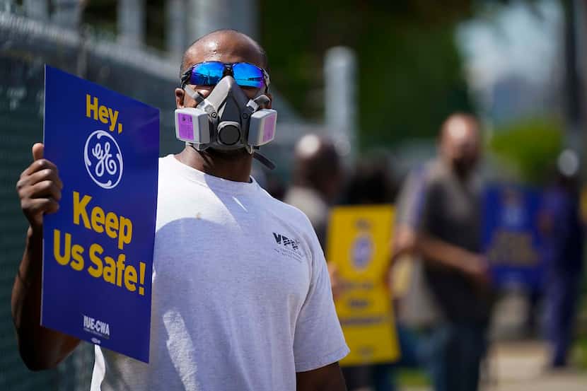 Cornelius Hunt wears a mask and holds a sign as he protests with fellow Iworkers outside GE...