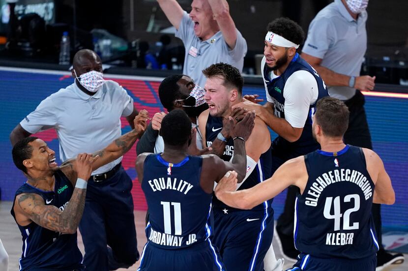 Luka Doncic #77 of the Dallas Mavericks celebrates with teammates after making a...