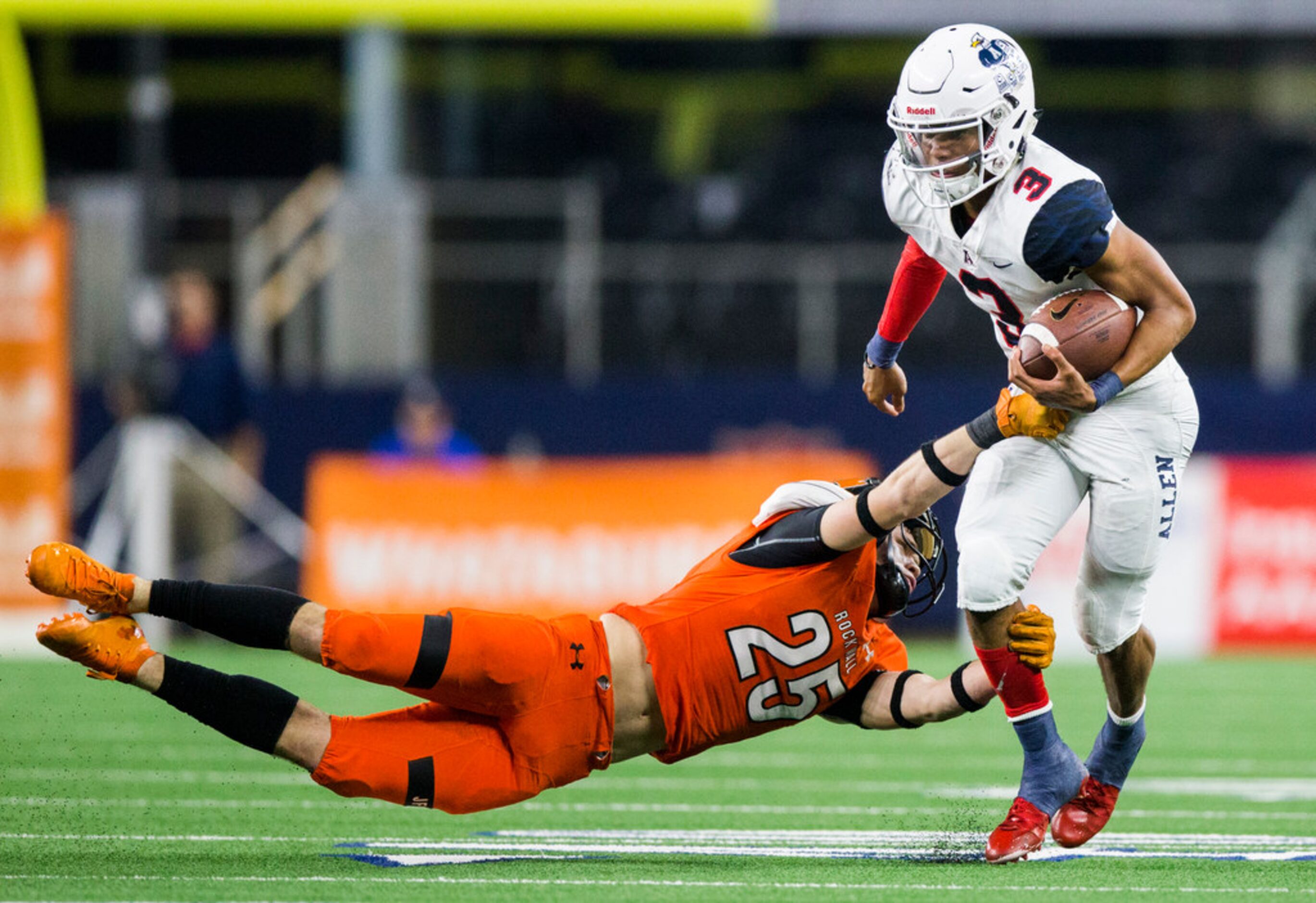 Allen quarterback Raylen Sharpe (3) is tackled by Rockwall defensive back Corey Kelley (25)...