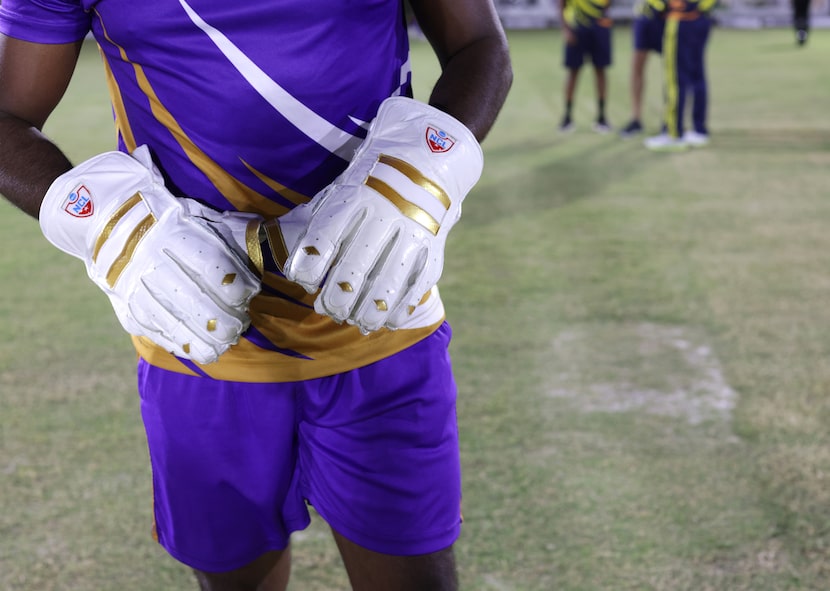 A player displays his cricket gloves at UT Dallas Monday night. Although cricket is a...