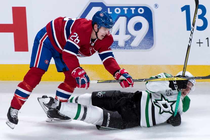Montreal Canadiens defenseman Mike Reilly (28) sends Dallas Stars centre Tyler Pitlick (18)...