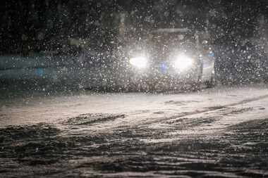 Cars move slowly through falling snow on Plano Road near Renner Road as a second winter...