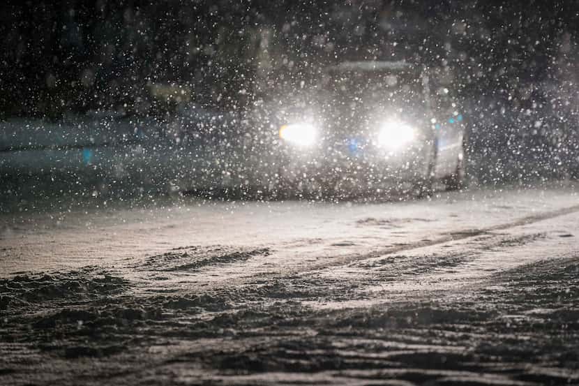 Cars move slowly through falling snow on Plano Road near Renner Road as a second winter...