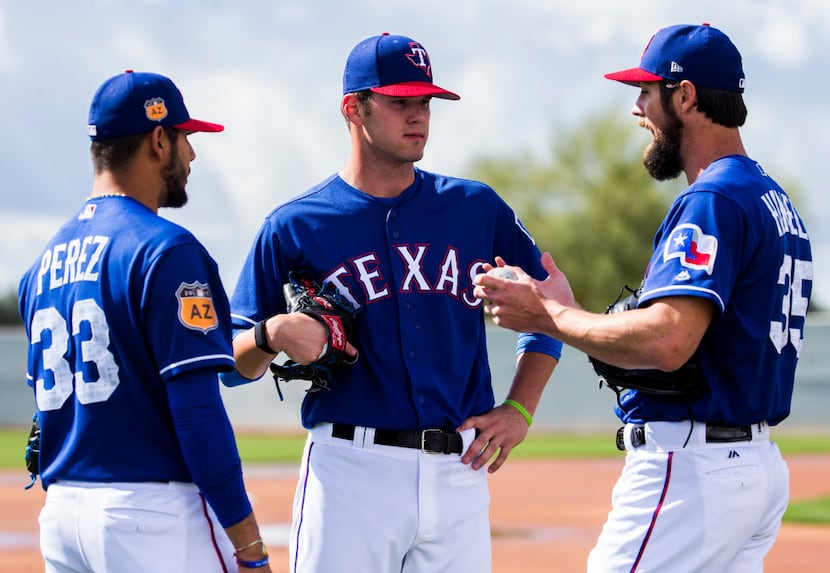 Minor league pitcher Cole Ragans, center, gets advice from starting pitcher Martin Perez...