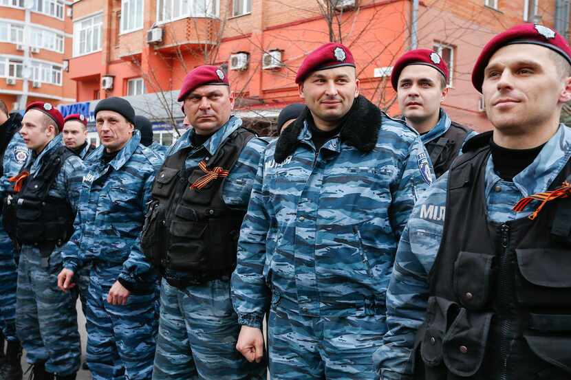 A group of Ukraine's now-defunct riot police officers stand in their uniforms, as they guard...