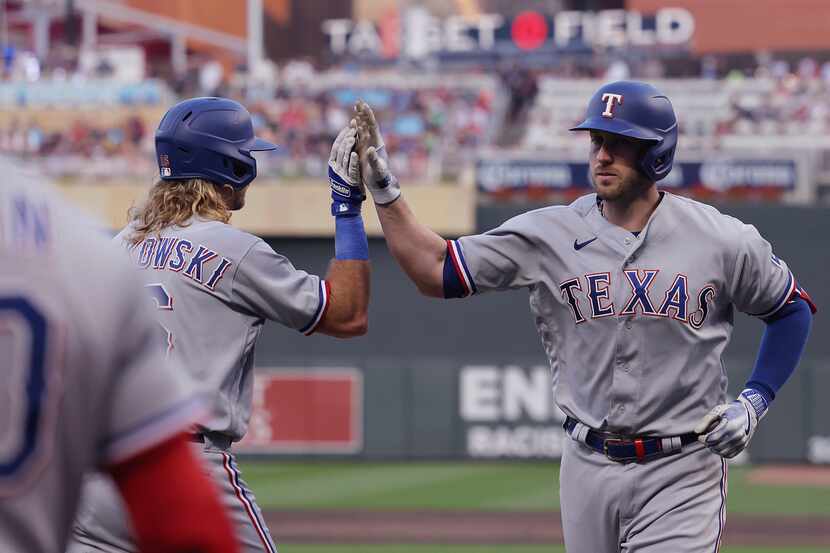 Texas Rangers' Mitch Garver, right, high-fives Travis Jankowski after Garver hit a home run...