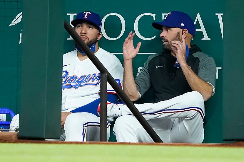Texas Rangers manager Chris Woodward talks with catcher Jose Trevino in the dugout during...