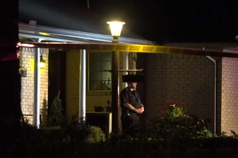 A Dallas police officer stands outside a home in the White Rock neighborhood where a woman...
