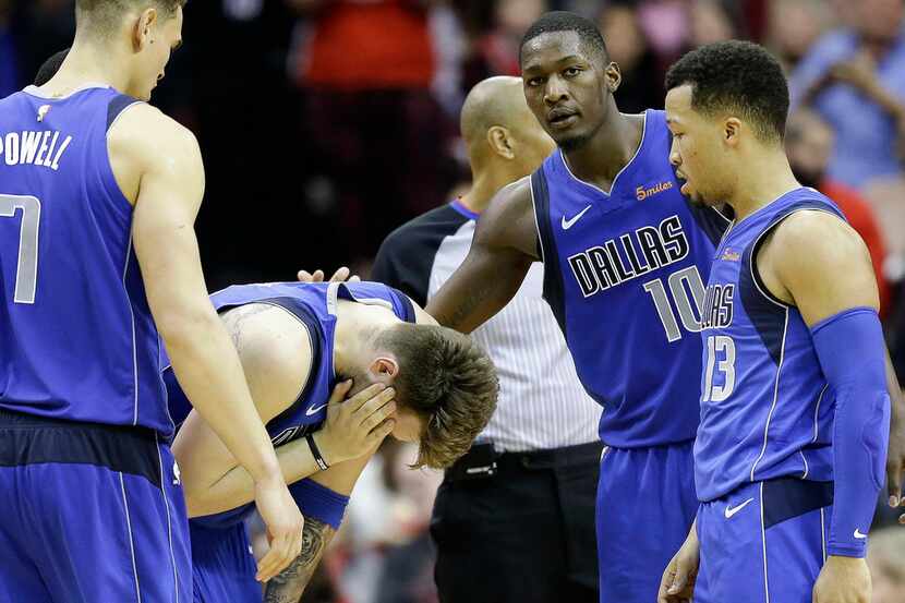 Dallas Mavericks forward Luka Doncic, second from left, hold his face after being fouled...