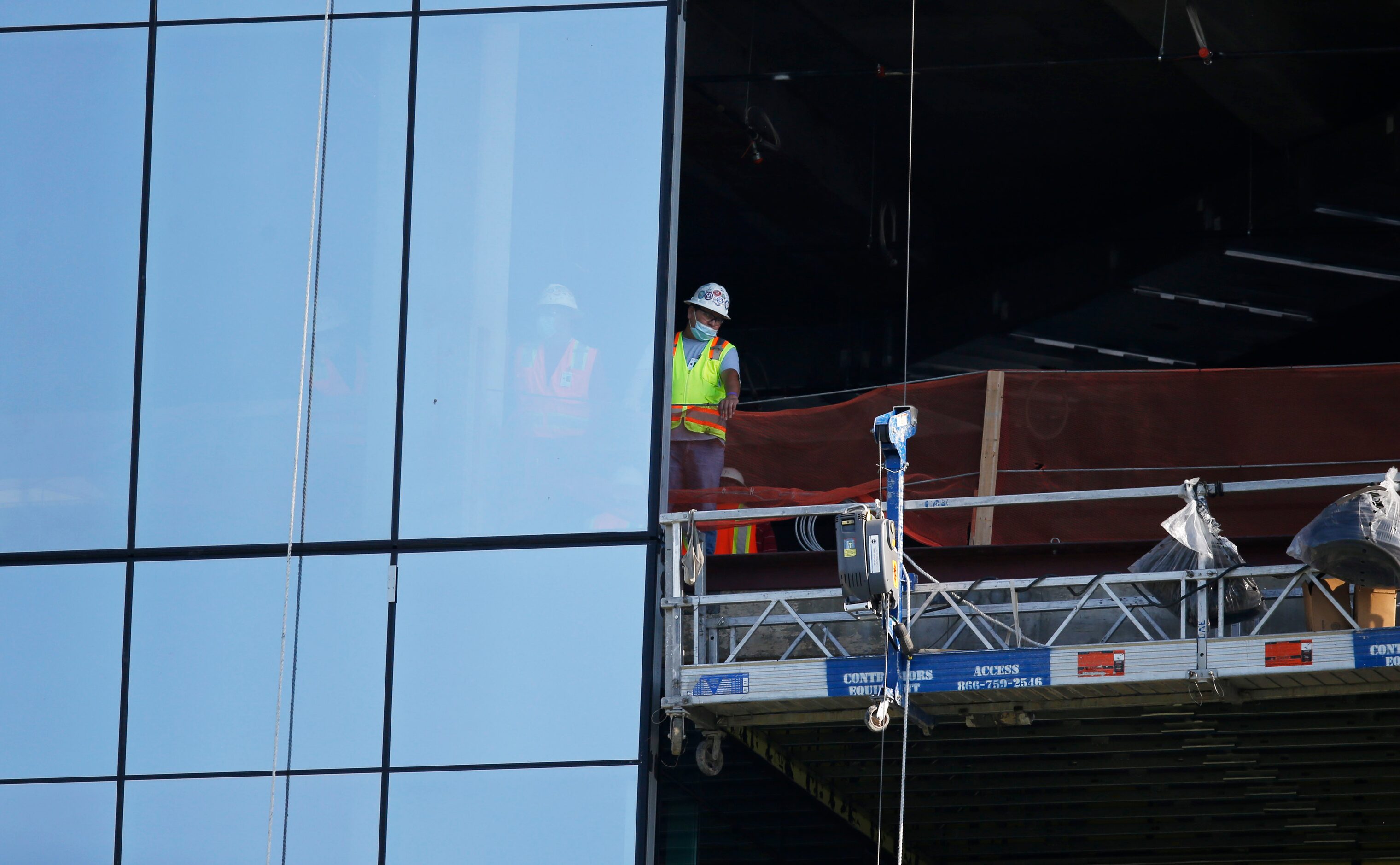 A construction crew watches practice from the work site of the new Texas headquarters for...