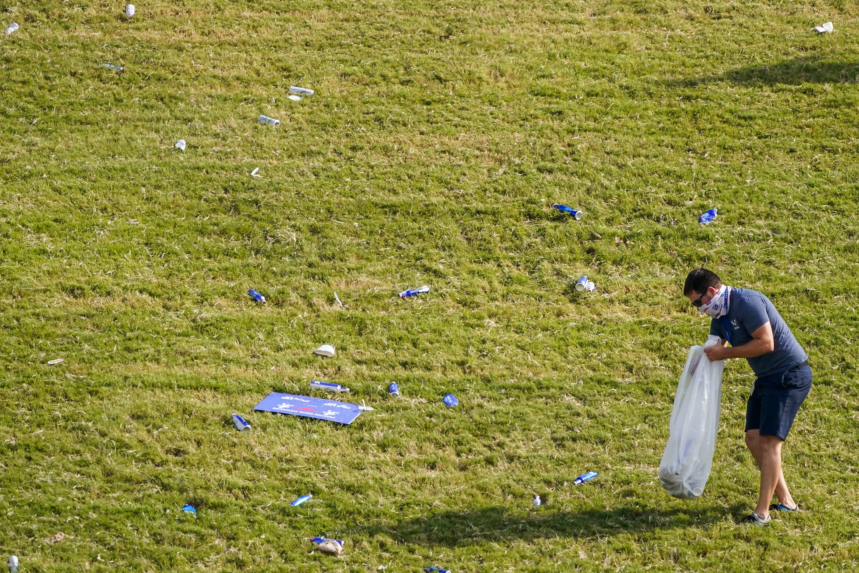 A worker clears debris from the grass after law enforcement cleared SMU students from the...