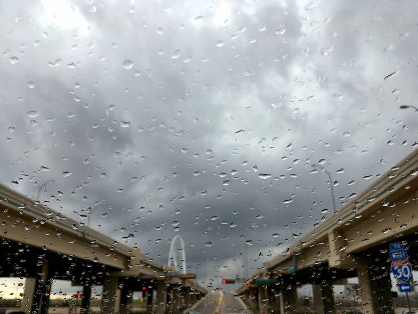 Light rain falls downtown as storms roll through the area, seen though a windshield at...